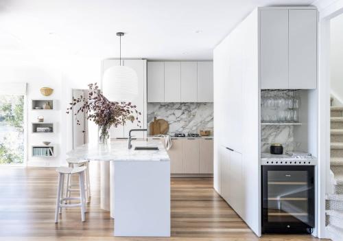 a kitchen with white cabinets and a white island at Calabash Bay Lodge in Berowra