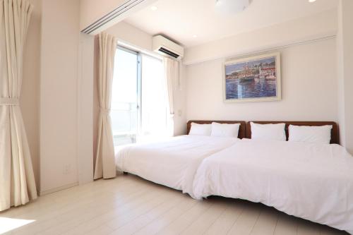 a white bedroom with a large bed and a window at PG Kuromon in Osaka