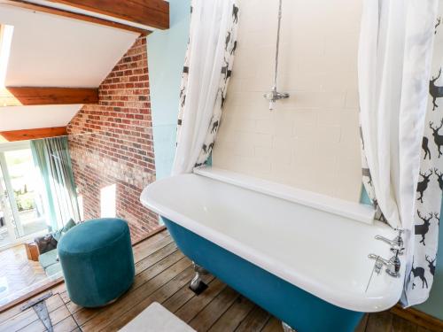 a bathroom with a white tub and a blue stool at The Cow Byre in Kirkby Stephen