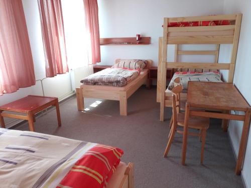 Habitación con 2 camas, litera y mesa. en Penzion Athéna - sportovní areál, en Nová Včelnice