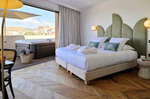 - une chambre avec un lit et un balcon avec une baignoire dans l'établissement Hôtel & Spa Rocabella, à LʼÎle-Rousse