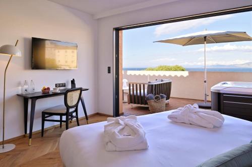 a hotel room with a bed and a view of the ocean at Hôtel & Spa Rocabella in LʼÎle-Rousse