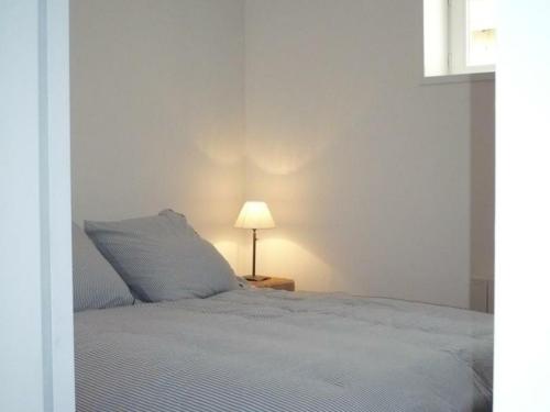 um quarto branco com uma cama e um candeeiro em Gîte Saint-André-d'Apchon, 2 pièces, 2 personnes - FR-1-496-142 em Saint-André-dʼApchon