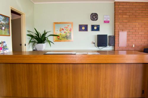 a wooden reception desk with a potted plant on top at Crystal Fountain Motel Albury in Albury