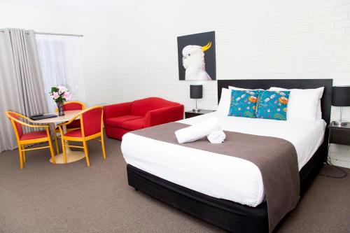 a bedroom with a large bed and a red chair at Crystal Fountain Motel Albury in Albury