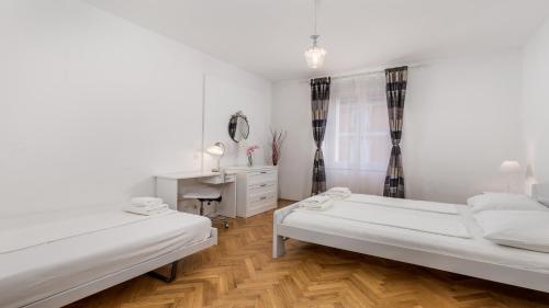 a white bedroom with two beds and a desk at Main Square - Lloyd apartment in Rijeka