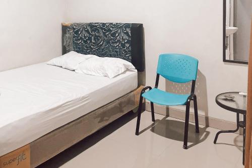 ein Bett mit einem blauen Stuhl in einem Zimmer in der Unterkunft Almira Homestay Ambon Mitra RedDoorz in Ambon