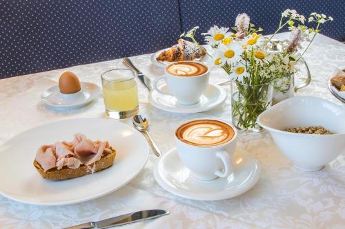 a table with cups and plates of food and coffee at B&B - Hotel Ciasa Rü Blanch in San Cassiano