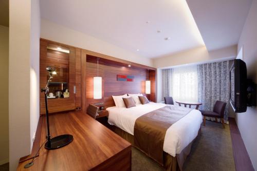 秋田市にあるホテルメトロポリタン秋田のベッドとテレビが備わるホテルルームです。
