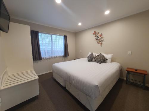 a bedroom with a large white bed and a window at ASURE Albert Park Motor Lodge in Te Awamutu