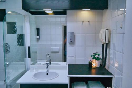 a bathroom with a sink and a shower and a phone at Vincents Bed&Bistro in Etten-Leur