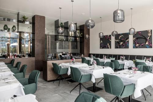 a restaurant with white tables and green chairs at NIDUM - Casual Luxury Hotel in Seefeld in Tirol