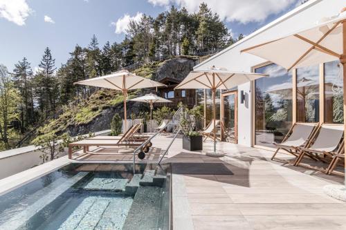 uma piscina com cadeiras e guarda-sóis ao lado de uma casa em NIDUM - Casual Luxury Hotel em Seefeld no Tirol