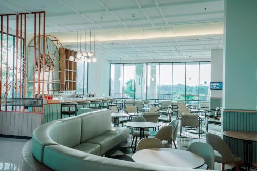 un ristorante con tavoli, sedie e finestre di Luwansa Hotel and Convention Center Manado a Manado