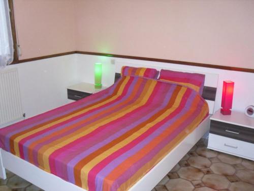 a bedroom with a bed with a colorful striped blanket at Gîte indépendant avec jardin clos, terrasse et wifi, au centre de Senlis, animaux acceptés - FR-1-376-52 in Senlis