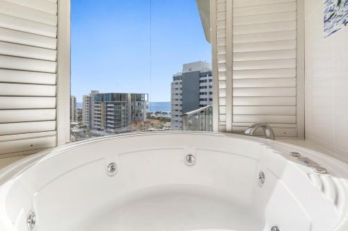 een wit bad in een kamer met een raam bij Silver Sapphire on Sixth Penthouse in Maroochydore