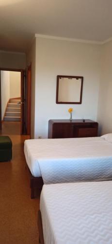 a hotel room with two beds and a mirror at Pensão Continental Machado in Caldelas