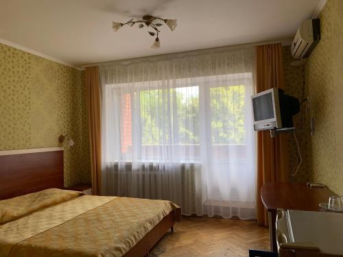 a bedroom with a bed and a window with a television at Hotel Prydesnyansky in Chernihiv