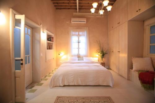 a bedroom with a large white bed and a window at Four Hearts - Acre's Sea Side Suite in ‘Akko