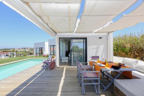 a patio with a table and chairs next to a pool at Like-home-T2 house, pool, AC, garden in Ericeira