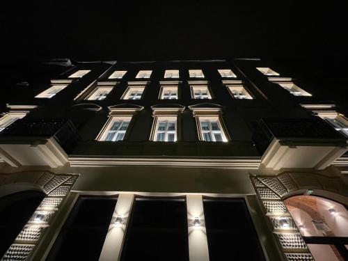 ein hohes Gebäude mit beleuchteten Fenstern in der Nacht in der Unterkunft 1891 Garni Hotel in Krakau
