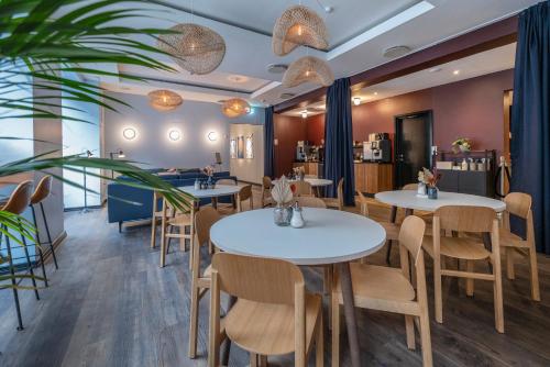 a restaurant with white tables and chairs and a bar at Motel One Copenhagen in Copenhagen