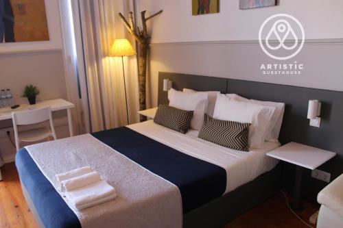 a hotel room with a large bed with a table and a table at ArtisticGuesthouse in Tomar