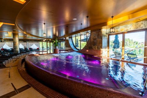 una gran piscina cubierta con luces moradas en un edificio en Allure Healthy Hotel & Spa, en Eger