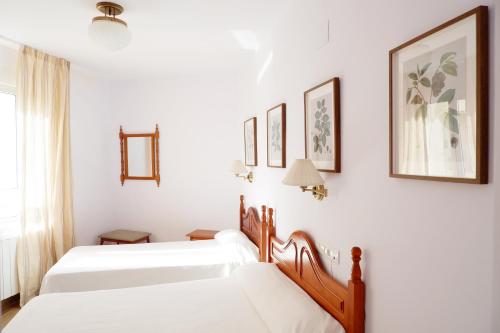 two beds in a room with white walls at Hotel Andalucia in Lanjarón