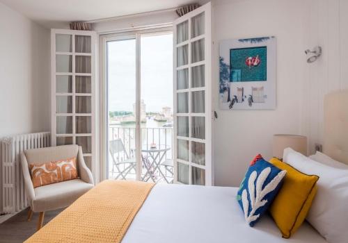 ein Schlafzimmer mit einem Bett und einem Stuhl sowie einem Balkon in der Unterkunft Tour de Nesle La Rochelle Vieux Port 3 etoiles in La Rochelle