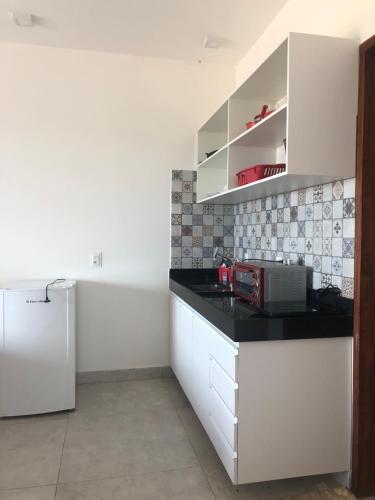 a kitchen with white cabinets and a white refrigerator at Gostoso White in São Miguel do Gostoso