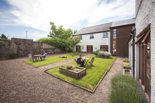 a man sitting in a yard with a garden at Bushmills Youth Hostel in Bushmills