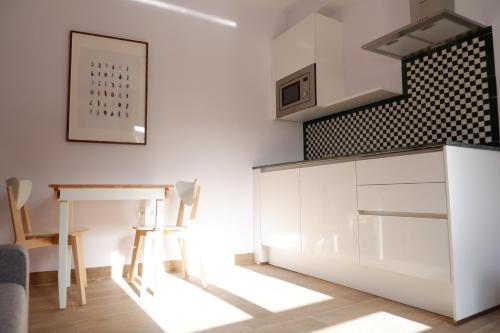 a kitchen with white cabinets and a table and chairs at Hotel Andalucia in Lanjarón