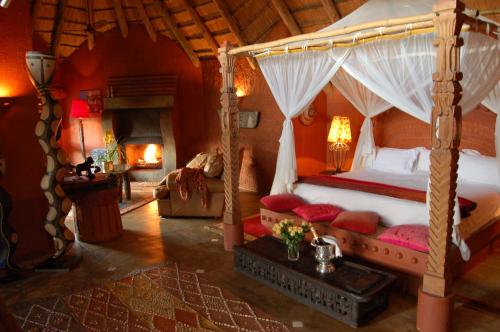a bedroom with a canopy bed and a fireplace at Timamoon Lodge in Hazyview