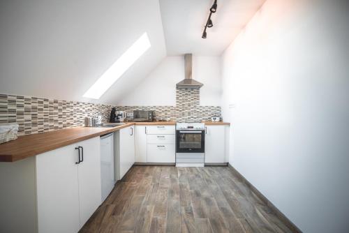 an attic kitchen with white cabinets and wood floors at Pataky Apartmanok in Veszprém