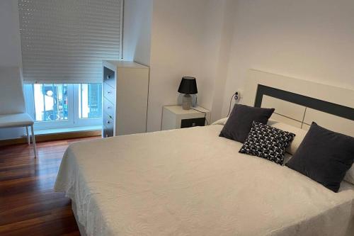 um quarto com uma grande cama branca e 2 almofadas em Apartamento en Boiro em Boiro