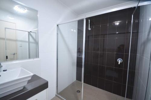 y baño con ducha acristalada y lavamanos. en Bundys Best! Modern Luxury in the heart of town, en Bundaberg