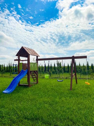 a playground with a slide in a field of grass at Luksusowe całoroczne domki z widokiem Janowiec in Janowiec