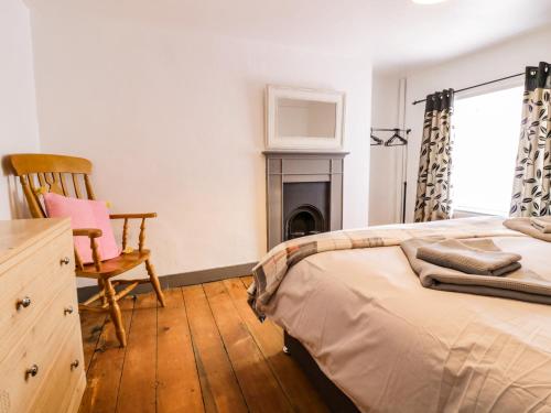 a bedroom with a bed and a chair and a fireplace at Arosfa in Bala