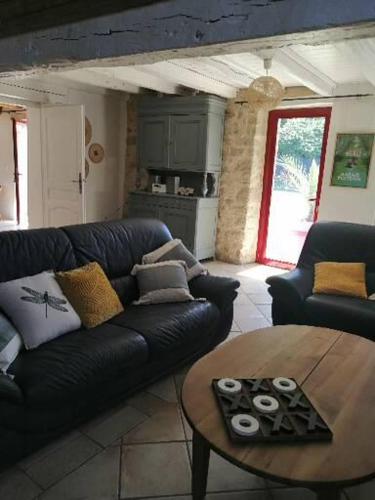 un salon avec un canapé en cuir noir et une table dans l'établissement Le cottage de l'étang, à Le Tablier