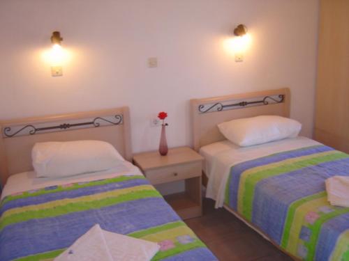 a bedroom with two beds and a vase with a flower at Vassilis Studios in Anaxos