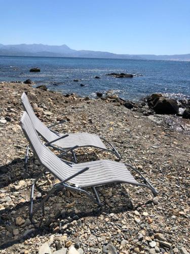 two chairs sitting on a rocky beach near the water at Dream House Efi in Ravdhoúkha