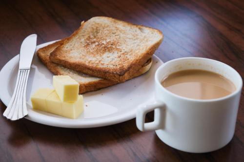 a plate with toast and butter and a cup of coffee at Zen Manali by Keekoo Stays in Manāli
