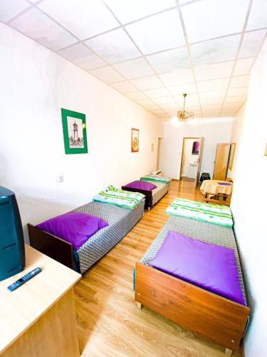 a room with three beds in it with purple sheets at Schronisko Młodzieżowe PTSM "Alko" in Rzeszów