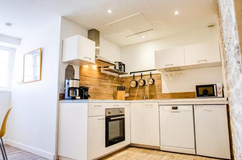 une cuisine avec des armoires blanches et une cuisinière dans l'établissement 350 m de la plage - Bel appartement pour 4, à Penmarcʼh