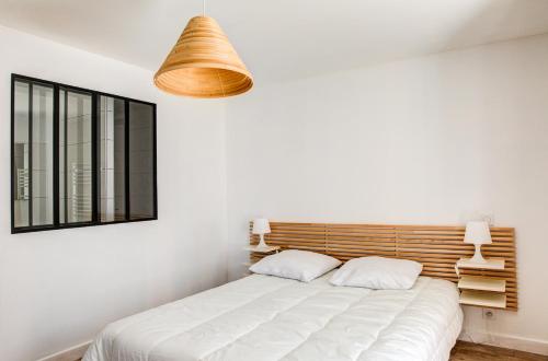 een slaapkamer met een wit bed en een houten hoofdeinde bij Charmant appartement pour un sejour authentique au coeur du Finistere in Penmarcʼh