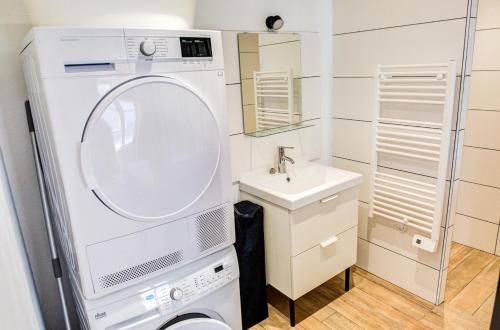 une salle de bain avec une machine à laver et un lavabo dans l'établissement 350 m de la plage - Bel appartement pour 4, à Penmarcʼh