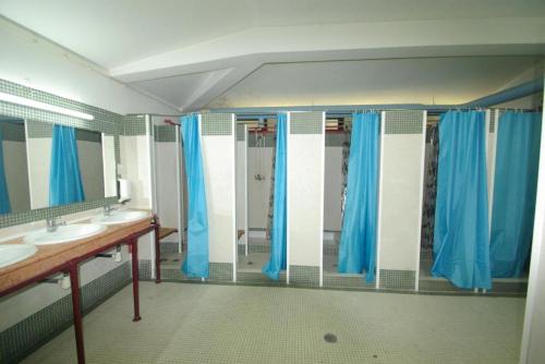 a bathroom with two sinks and blue shower curtains at HI Almada - Pousada de Juventude in Almada