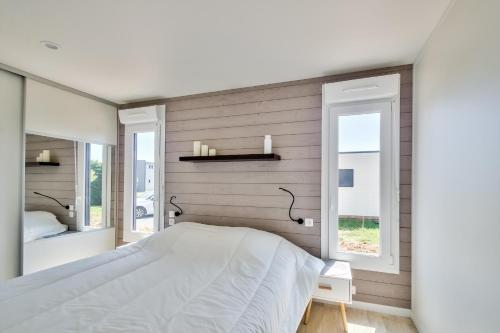 a bedroom with a white bed and two windows at Chalet pour 8 dans résidence avec piscine chauffée in Brétignolles-sur-Mer