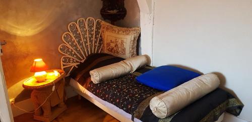 a small bed with a blue pillow and a lamp at Les Petites Forges in Auxonne
